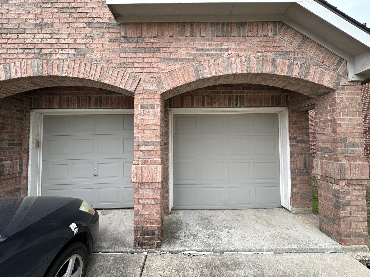 New residential garage door installation on a brick home